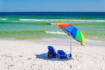 Umbrella and chairs set up at beach shoreline. Beautiful tropical Gulf Coast ocean beach white sands and sea. Vacation tourist travel destination for fun and relaxation.