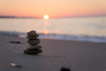 Zen stone sculpture - pebble - and calm sea at sunrise in Tunisia. Vacation.