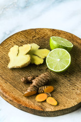 turmeric and ginger roots on a cutting board, cut with lime