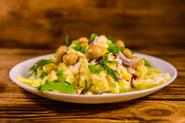 Salad with marinated mushrooms, eggs, red onion, boiled potato and mayonnaise on wooden table