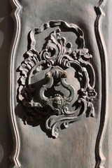 Baroque carved wooden door detail with floral decoration and door knocker in Pisa, Italy