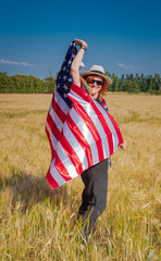 woman in a wheat field with a USA flag