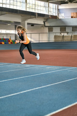 Fototapeta na wymiar Athletic blonde woman training at indoor stadium