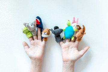 Hands of a child with finger puppets, toys, dolls close up on white background - playing puppet theatre and children entertainment concept