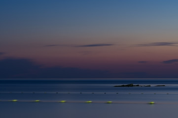 Long exposure. The sea against the twilight sky. Late sunset. The stone protrudes from the water....