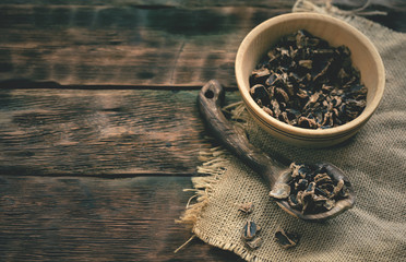 Dryed carob tree bark in a wooden bowl on a table.