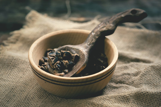 Dryed carob tree bark in a wooden bowl on a table.