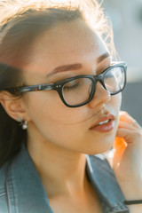 Beautiful young girl on the streets of modern town in glasses. Leisure, beauty, fashion concept