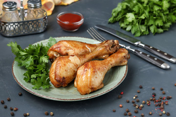 Chicken drumsticks, baked in a marinade of ketchup, soy sauce and balsamic vinegar on a plate on a dark background