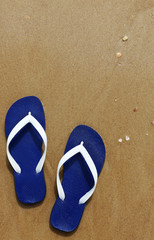 Fototapeta na wymiar Blue slippers on the sandy seashore