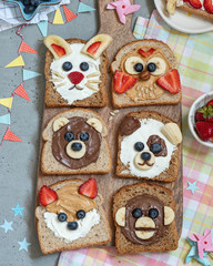Funny animal faces toasts with spreads, banana, strawberry and blueberry