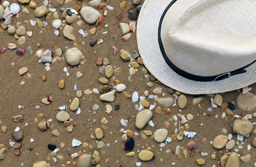 Fototapeta na wymiar Straw hat on a sandy and stone beach