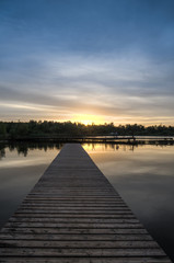 Pier stretching into the lake on a background of dawn. Vertical frame