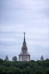 Fototapeta na wymiar The main building of the Moscow state University rises above the trees. Russia, Moscow. The building of Stalin's times
