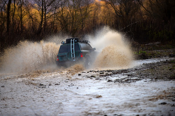 Offroading. Scene of wather splash in off-road racing. A car during a tough off-road competition diving in a muddy pool. Extreme weekends. © Volodymyr