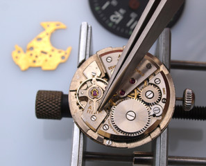 watchmaker working with tweezers into vintate mechanic watch movement