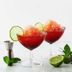 Red Frozen Margarita, refreshing cocktail on the table and lime with mint