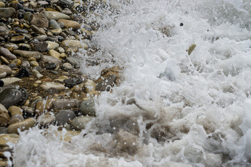 Obraz premium pebble stones on the sea beach, the rolling waves of the sea with foam