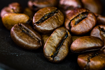 Brown roasted coffee beans on black background, close up, macro