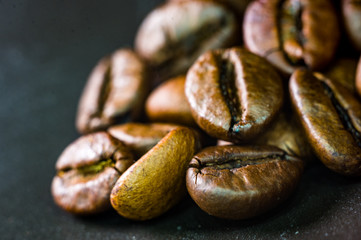 Brown roasted coffee beans on black background, close up, macro