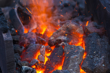 blacksmith furnace with burning coals, tools, and glowing hot metal workpieces