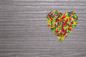 Multicolored heart shaped sticks isolated on grey wooden background with copy space.