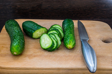 Steel knife and sliced ​​cucumbers on a cutting board for healthy food close up for vegetarians