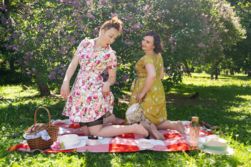 two pretty pin up ladies having nice picnic in the city park in a sunny day together. girls friends...