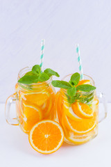 Infused water with fruits on white background. Mug delicious refreshing drink of mix fruits with mint on white background. Iced summer drink in mason jar. Minimalism