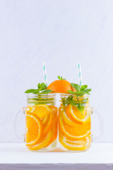 Infused water with fruits on white background. Mug delicious refreshing drink of mix fruits with mint on white background. Iced summer drink in mason jar. Minimalism