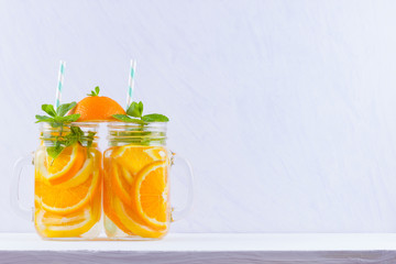 Infused water with fruits on white background. Mug delicious refreshing drink of mix fruits with mint on white background. Iced summer drink in mason jar. Minimalism