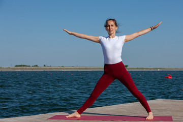 Fototapeta premium Pretty woman practicing yoga at a lake