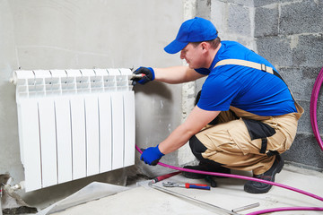 plumber at work. Installing water heating radiator