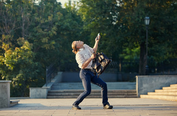 Happy businessman jumping with cityscape background. The best day. Young  man in formal wear...
