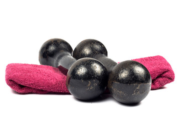 Two vintage cast iron black weights stacked on a pink towel on white background