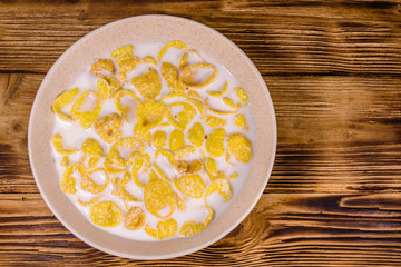 Ceramic plate with cornflakes and milk on a wooden table. Healthy eating. Top view
