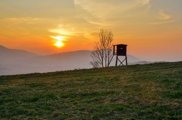 Beautiful mountain colorful landscape. Hunting pulpit and the setting sun over the hills.
