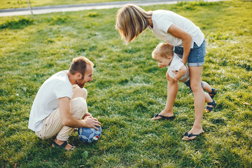 Fototapeta premium Family in a summer park. Mother in a white t-shirt. Cute little boy with a dad