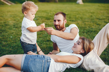 Family in a summer park. Mother in a white t-shirt. Cute little boy with a dad