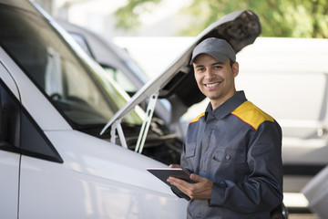 Mechainc using a tablet in front of a van © Minerva Studio