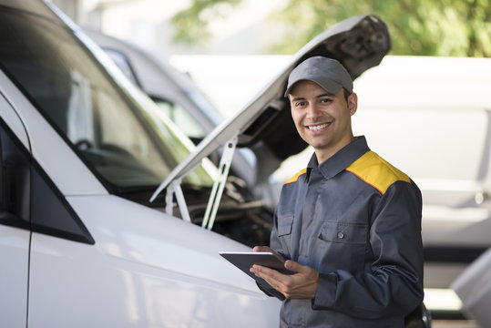 Mechainc using a tablet in front of a van