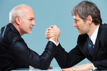 Two businessmen facing off arm wrestling