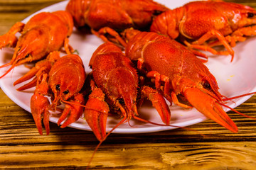 Plate with boiled crayfishes on wooden table