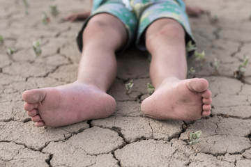 Fainting from heat, dehydration in a child. Children's feet lie on cracked dried earth.