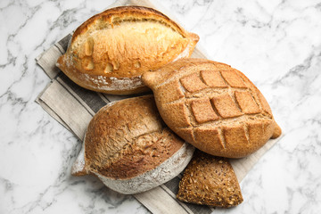 Different kinds of fresh bread on marble table, top view