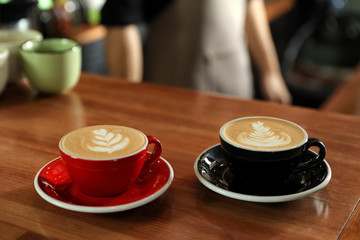 Cups of coffee on wooden counter in bar. Space for text