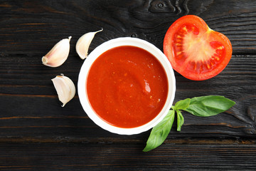 Flat lay composition with bowl of tomato sauce on wooden table