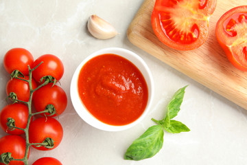 Flat lay composition with bowl of sauce and tomatoes on light table