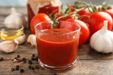 Composition with glass of tasty tomato sauce on wooden table