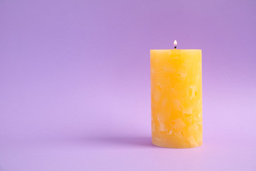 Alight wax candle on color background. Space for text